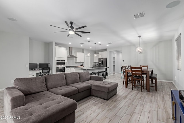 living room with a ceiling fan, baseboards, light wood-style floors, and recessed lighting