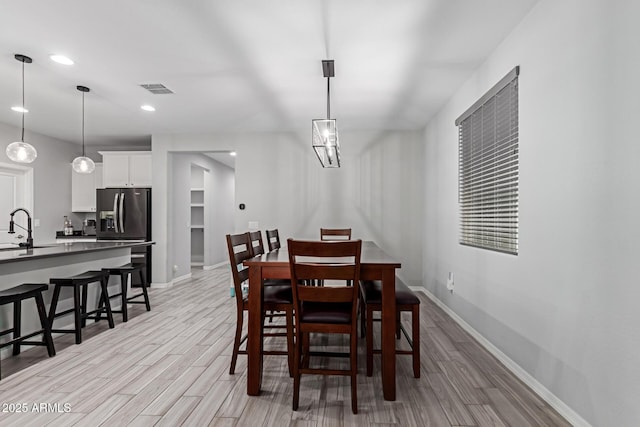 dining room featuring light wood-style flooring, baseboards, and recessed lighting