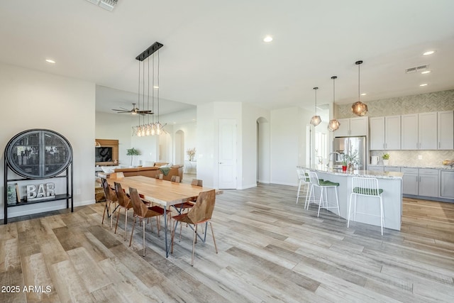 17324 E Quail Track Rd, Rio Verde, AZ 85263 - dining space with a ceiling fan, arched walkways, light wood finished floors, and visible vents