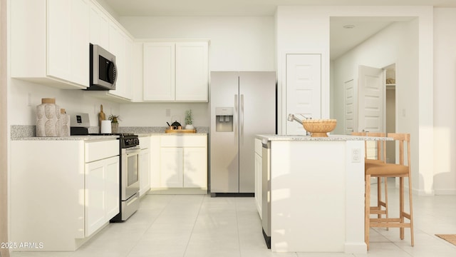 kitchen with light tile patterned flooring, a breakfast bar, stainless steel appliances, white cabinetry, and a kitchen island
