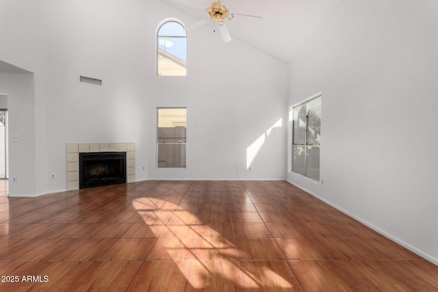 unfurnished living room featuring ceiling fan, tile patterned flooring, high vaulted ceiling, and a tile fireplace