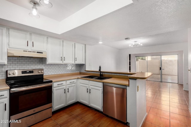 kitchen with premium range hood, sink, kitchen peninsula, stainless steel appliances, and white cabinets