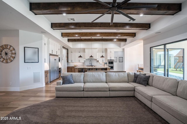 18125 W Montebello Ct Unit 67, Litchfield Park, AZ 85340 - living room featuring baseboards, light wood-style floors, beam ceiling, and a ceiling fan