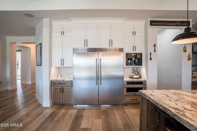 18125 W Montebello Ct Unit 67, Litchfield Park, AZ 85340 - kitchen featuring appliances with stainless steel finishes, wood finished floors, decorative backsplash, light stone countertops, and white cabinets