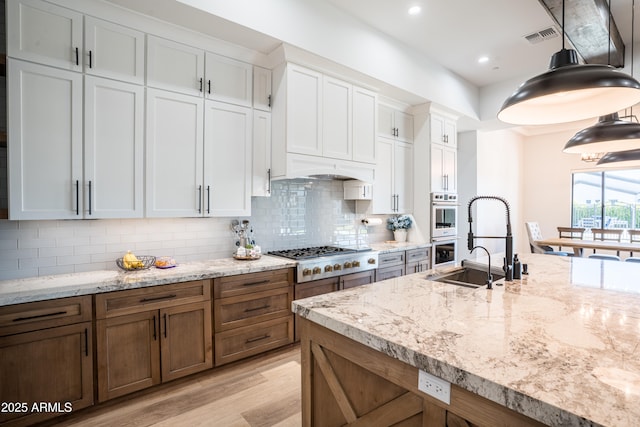 18125 W Montebello Ct Unit 67, Litchfield Park, AZ 85340 - kitchen featuring gas stovetop, double oven, light wood finished floors, white cabinets, and backsplash