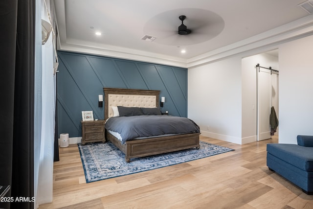 18125 W Montebello Ct Unit 67, Litchfield Park, AZ 85340 - bedroom featuring a barn door, light wood-style floors, baseboards, a decorative wall, and recessed lighting