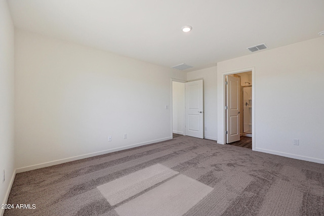 unfurnished bedroom featuring connected bathroom and dark carpet