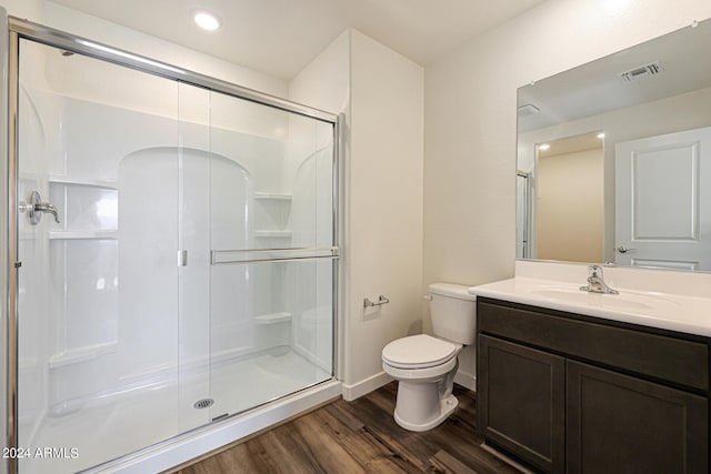 bathroom featuring a shower with door, hardwood / wood-style floors, toilet, and large vanity