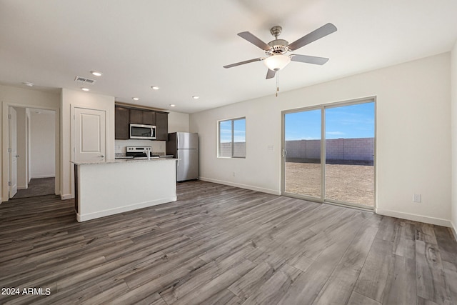 kitchen featuring light stone counters, dark hardwood / wood-style flooring, ceiling fan, dark brown cabinets, and appliances with stainless steel finishes