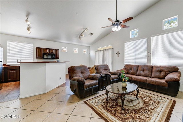 living room with ceiling fan, light tile patterned floors, rail lighting, and vaulted ceiling