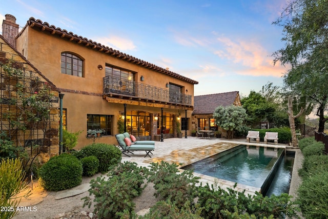 27050 N 103rd St, Scottsdale, AZ 85262 - back of property at dusk with a balcony, a patio area, stucco siding, an outdoor pool, and an outdoor hangout area
