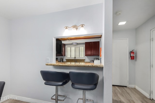 kitchen with sink, a breakfast bar area, and light wood-type flooring