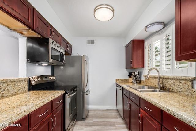 kitchen featuring light hardwood / wood-style floors, sink, light stone countertops, and stainless steel appliances