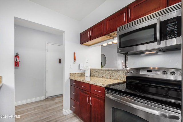 kitchen featuring light stone counters, light wood-type flooring, and stainless steel appliances