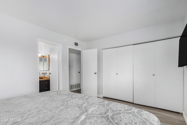 unfurnished bedroom featuring connected bathroom, a closet, and light wood-type flooring