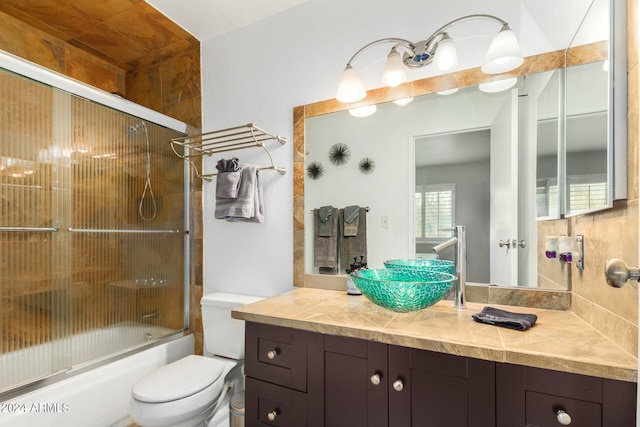 full bathroom featuring toilet, enclosed tub / shower combo, and vanity