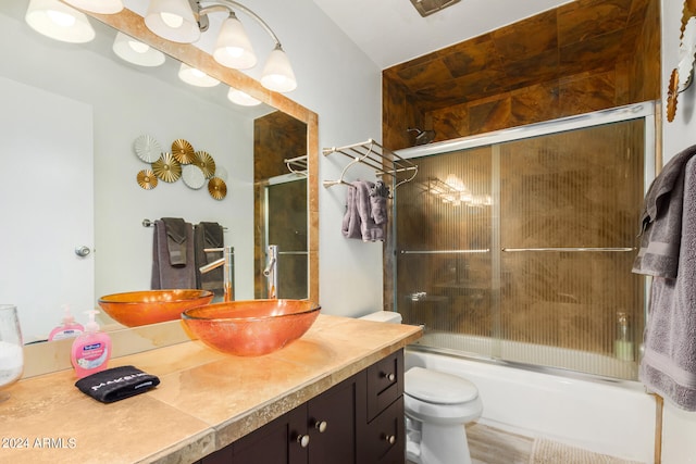 full bathroom with vanity, enclosed tub / shower combo, and toilet