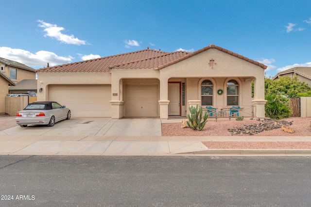 mediterranean / spanish house with a garage, fence, concrete driveway, a tiled roof, and stucco siding