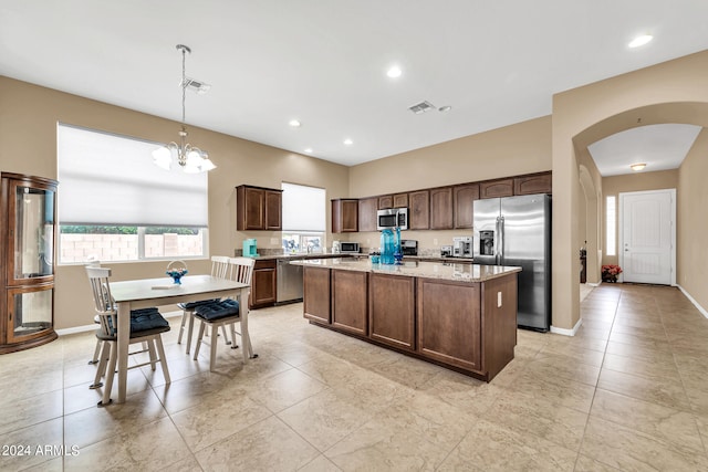 kitchen featuring stainless steel appliances, a center island, visible vents, and dark brown cabinets