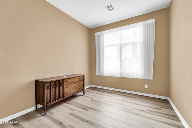 empty room with light wood-type flooring, visible vents, and baseboards