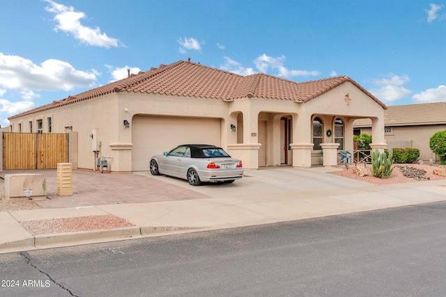 mediterranean / spanish house with driveway, a tile roof, an attached garage, and stucco siding