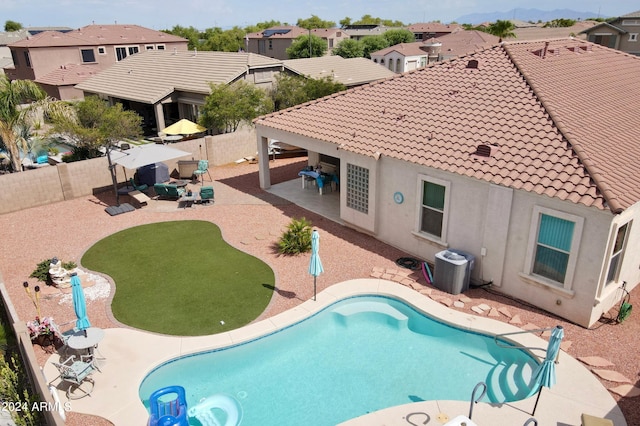 view of swimming pool with a fenced backyard, a residential view, central AC, and a patio