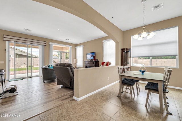 dining space with baseboards, visible vents, arched walkways, and a chandelier