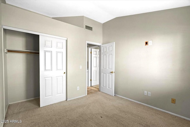 unfurnished bedroom featuring vaulted ceiling, light carpet, and a closet