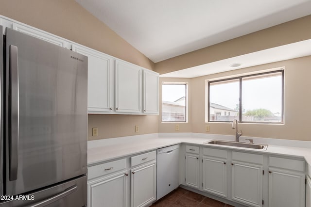 kitchen with white cabinets, stainless steel fridge, vaulted ceiling, dishwasher, and sink