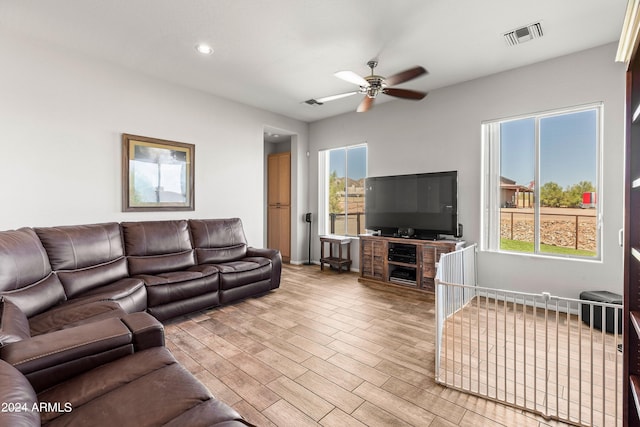 living room featuring ceiling fan, a fireplace, and light hardwood / wood-style flooring