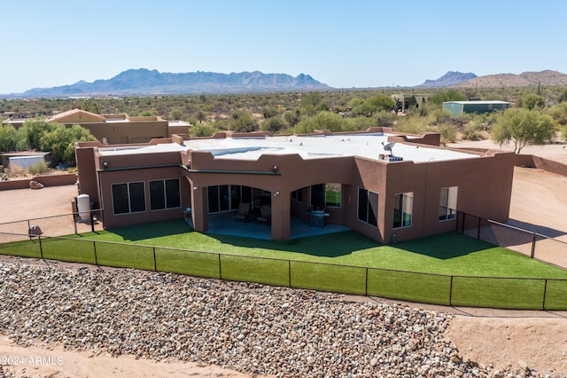 back of house with a lawn, a mountain view, and a patio