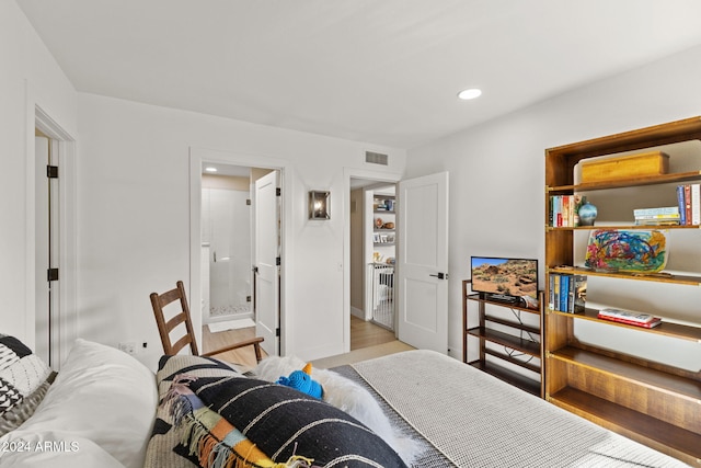 bedroom with connected bathroom and light hardwood / wood-style flooring