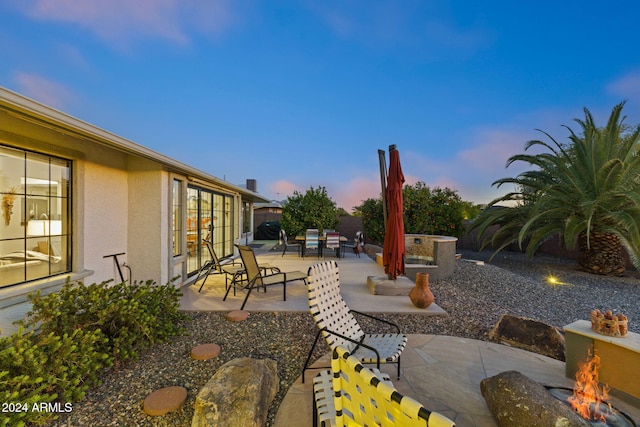 patio terrace at dusk featuring an outdoor fire pit