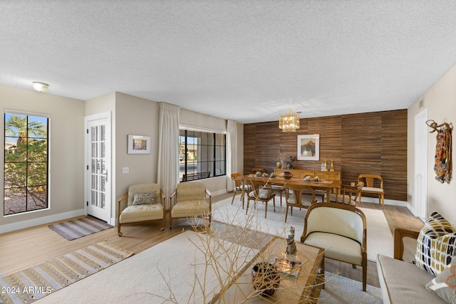 living room with wood walls, a textured ceiling, a wealth of natural light, and a chandelier