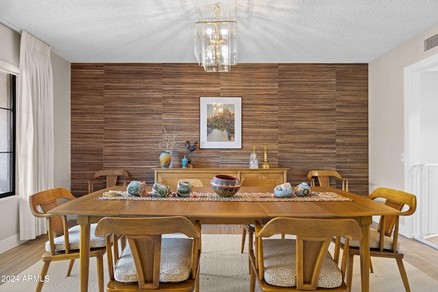 dining area featuring radiator, light hardwood / wood-style flooring, a chandelier, and a textured ceiling