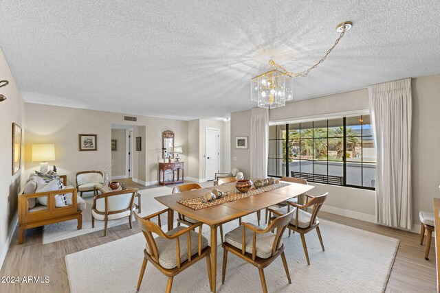 dining space featuring light hardwood / wood-style floors, a textured ceiling, and an inviting chandelier