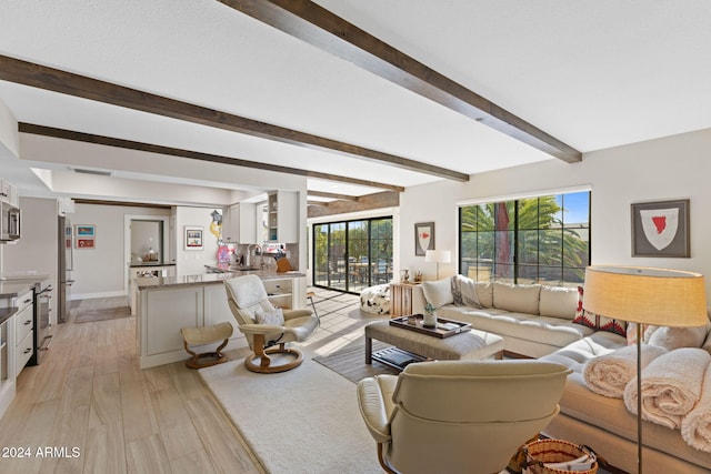 living room featuring beamed ceiling, light hardwood / wood-style flooring, and sink