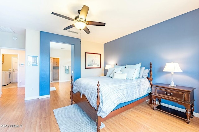 bedroom with washer and clothes dryer, ceiling fan, and wood-type flooring