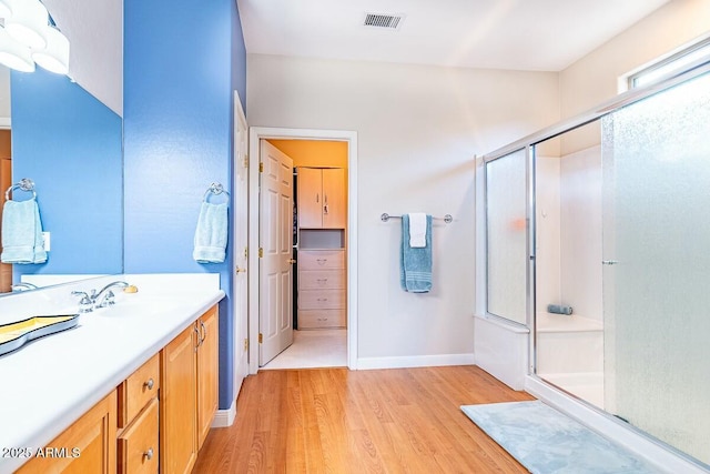 bathroom featuring hardwood / wood-style flooring, vanity, and an enclosed shower