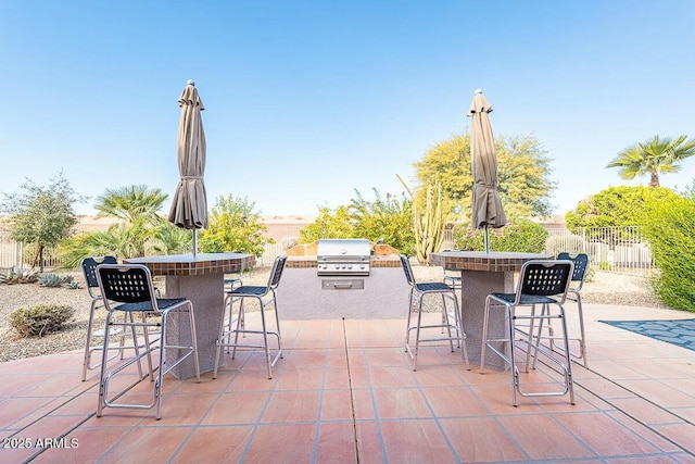 view of patio featuring a bar, exterior kitchen, and a grill