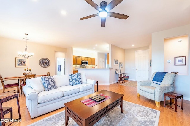 living room with light hardwood / wood-style floors and ceiling fan with notable chandelier