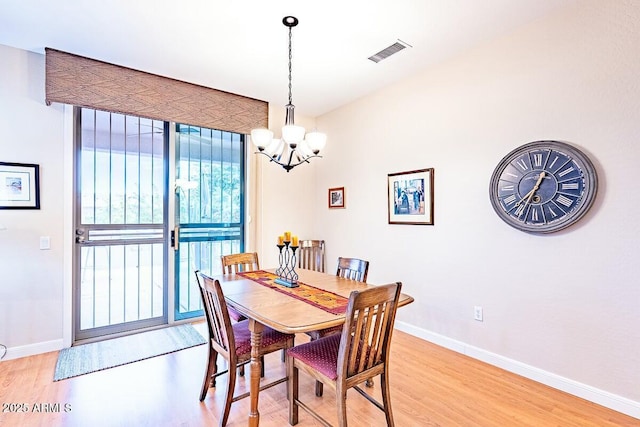 dining space with an inviting chandelier and light hardwood / wood-style flooring