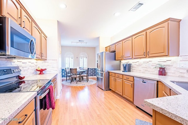 kitchen featuring decorative backsplash, appliances with stainless steel finishes, and light hardwood / wood-style floors