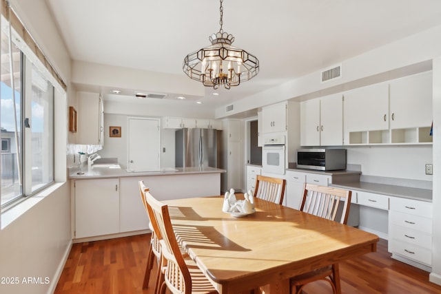 dining area featuring hardwood / wood-style floors, a notable chandelier, and sink