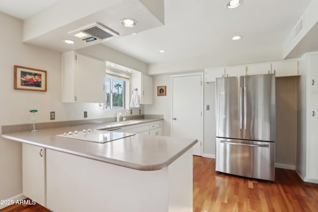 kitchen featuring white cabinetry, kitchen peninsula, stainless steel fridge, and black electric stovetop