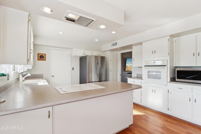 kitchen with light hardwood / wood-style flooring, stainless steel appliances, white cabinetry, and sink