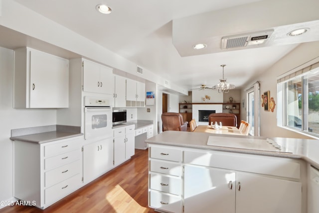 kitchen featuring ceiling fan, white oven, light hardwood / wood-style flooring, pendant lighting, and white cabinets