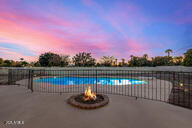 pool at dusk with a patio and a fire pit