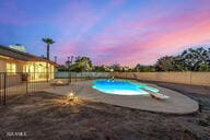 pool at dusk featuring a diving board and a patio