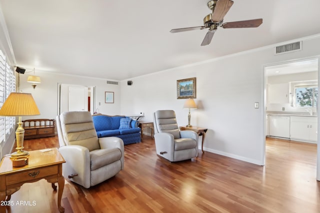 living room with hardwood / wood-style floors, ceiling fan, and crown molding